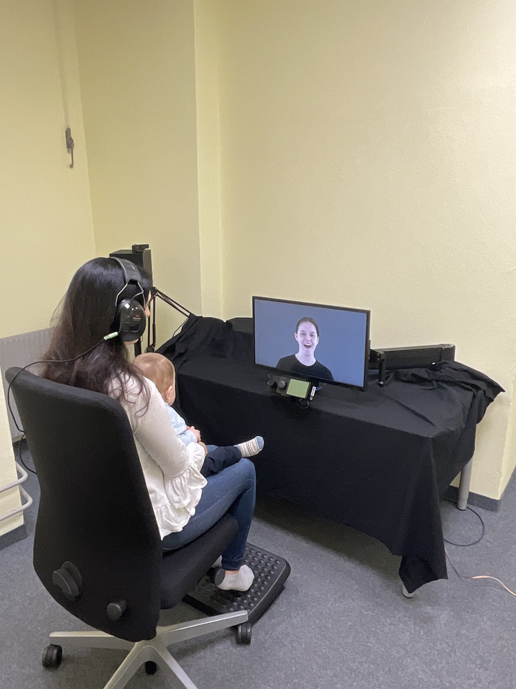Mother and child from behind while the baby is participating in an eye-tracking study.