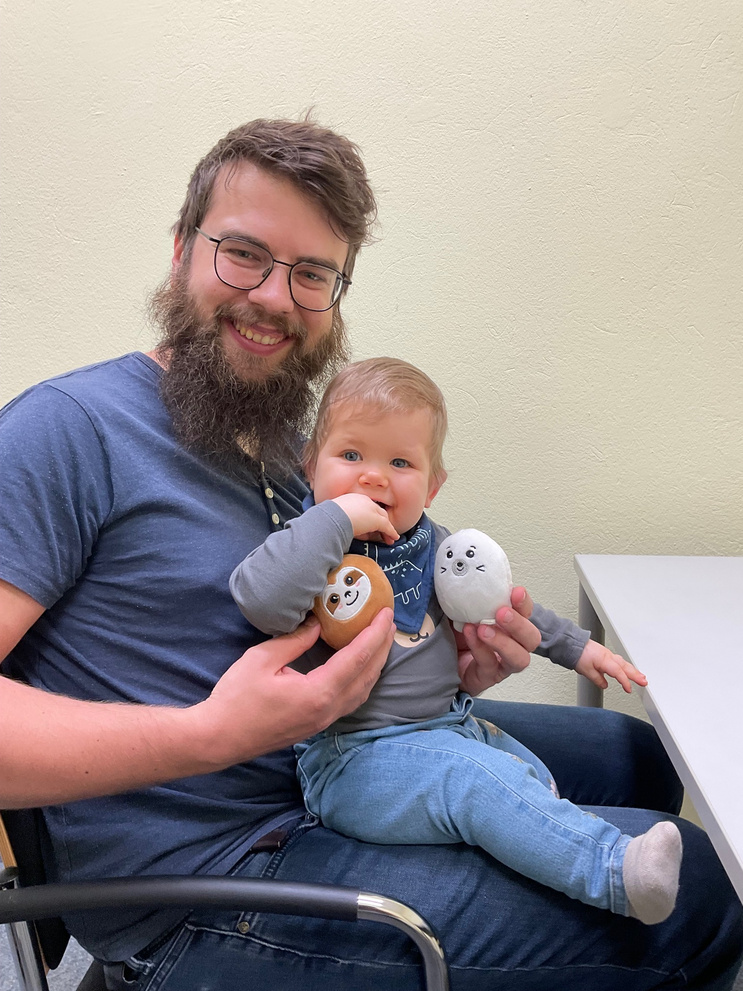 Papa mit Kleinkind am Schoß bei einer Verhaltensstudie mit Kuscheltieren
